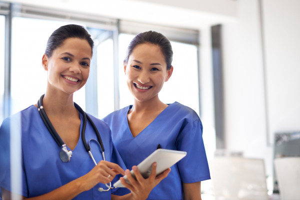 پرتره دو پرستار زن ایستاده با یک قرص دیجیتال در یک بیمارستان